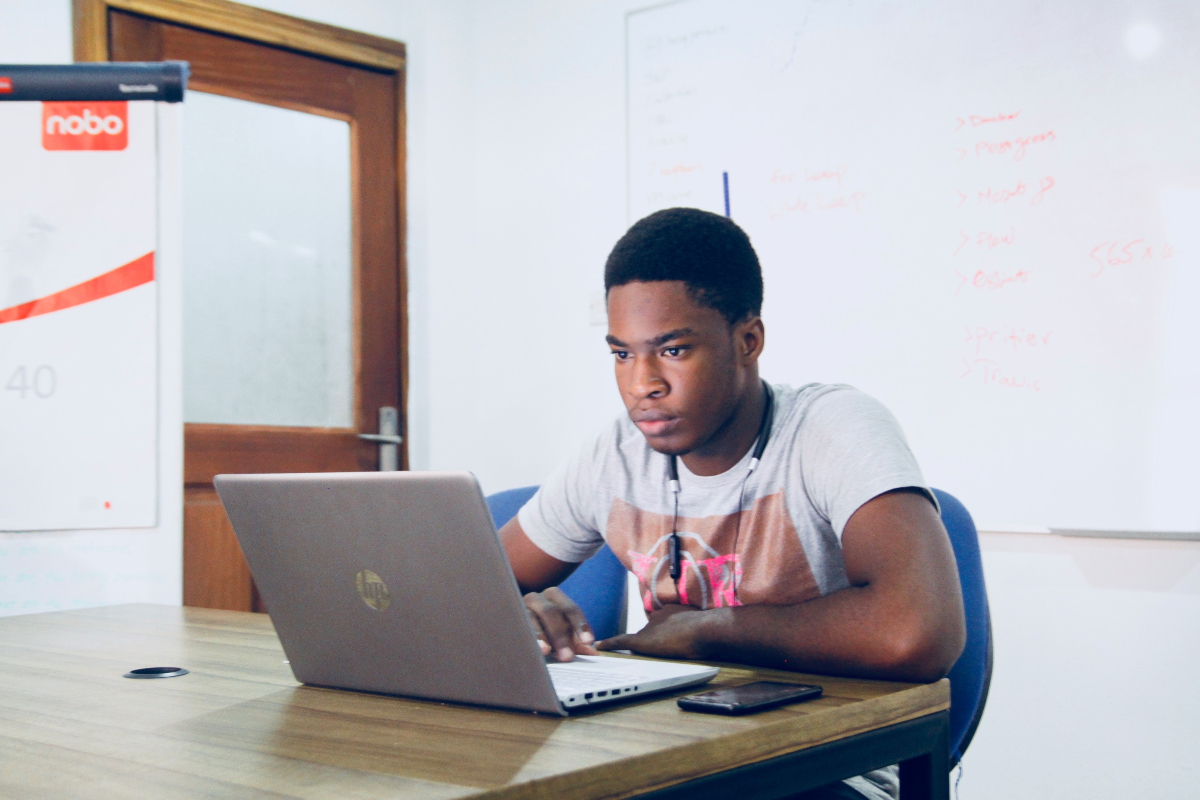 A Black man studies behavioral interview questions for interns on his laptop.
