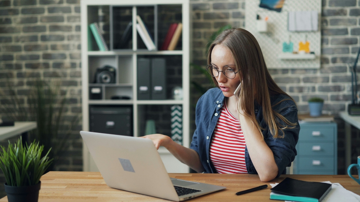 A white woman with long, dark blonde hair practices consultative selling on her computer